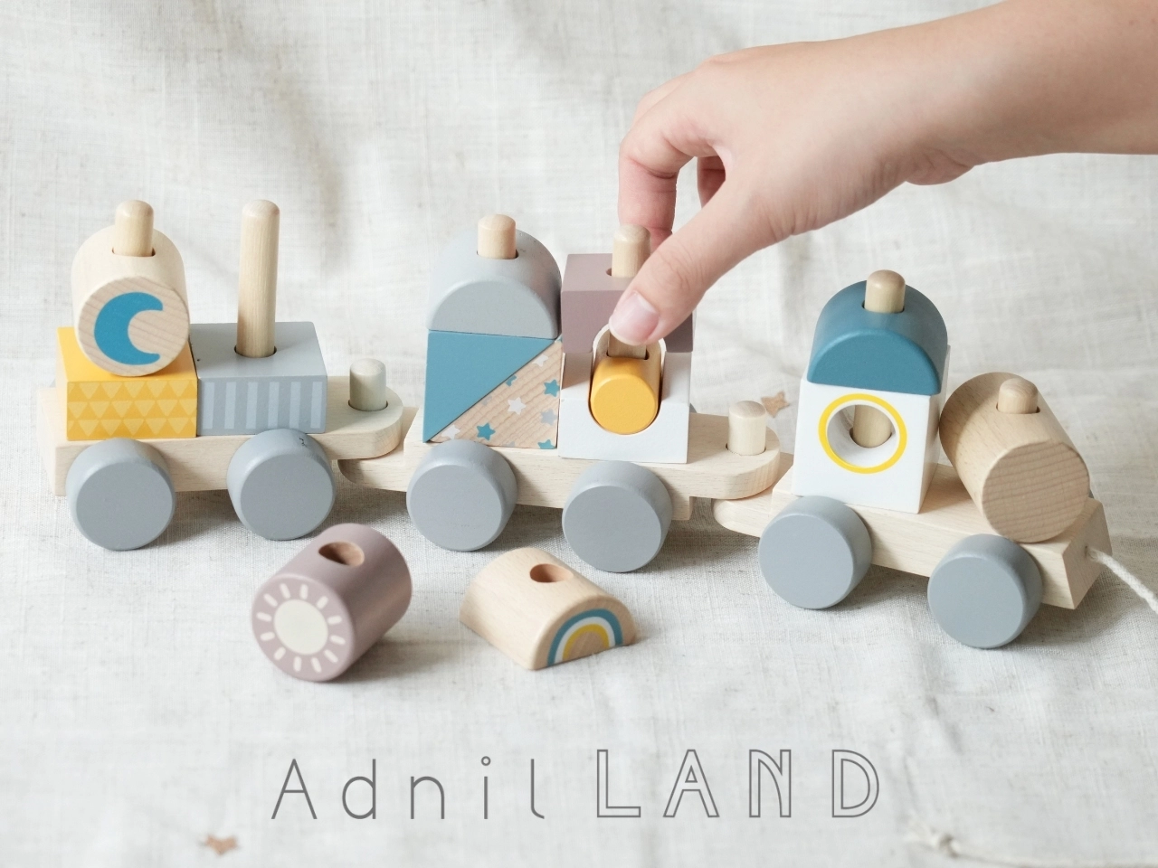 沛沛屋引進的日本母嬰選物 Adnil LAND 品牌商品，左圖為木製積木小火車玩具，右圖為大象、獅子、兔子、熊熊的針織手搖鈴